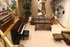 A lobby features a piano, sofas, and plants.