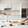 Technician installing kitchen cabinet hardware during a countertop and cabinet installation