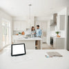 Designer and homeowner review remodeling plans in a bright modern kitchen with samples on the countertop.