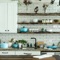 A kitchen with white cabinets, subway tile, and open wooden shelves holding cookware