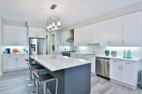 A modern kitchen with white cabinets, a dark island, and stainless steel appliances
