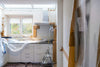 A kitchen under renovation with white cabinets covered in plastic and brown paper
