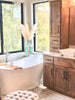 a bathroom with a tub, sink, cabinets and a window
