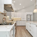 a kitchen with white cabinets and marble counter tops