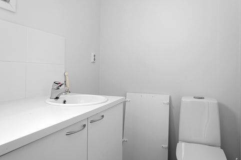 A white bathroom with a sink, toilet and mirror
