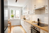 A kitchen with white cabinets and a stove top oven