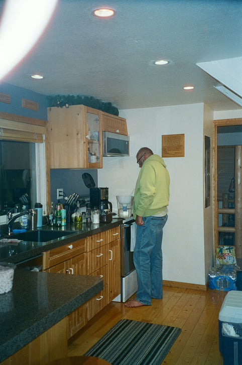 A man standing in a kitchen next to a stove top oven