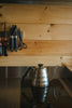 Coffee pot and kitchen tools hang on wood paneling.