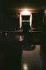 A person stands in a dimly lit kitchen.