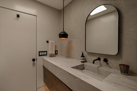 Modern bathroom with concrete sink and black faucet.