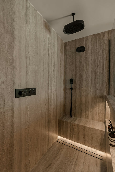 Modern shower stall with stone tiles and bench