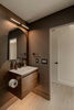 Modern bathroom with wooden vanity and arched mirror.