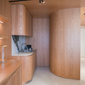 Modern kitchen with curved wooden cabinets and marble backsplash
