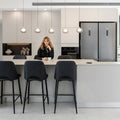Woman sitting at a modern kitchen island with bar stools.