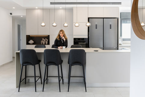 Woman sitting at a modern kitchen island with bar stools.