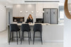 Woman sitting at a modern kitchen island with bar stools.