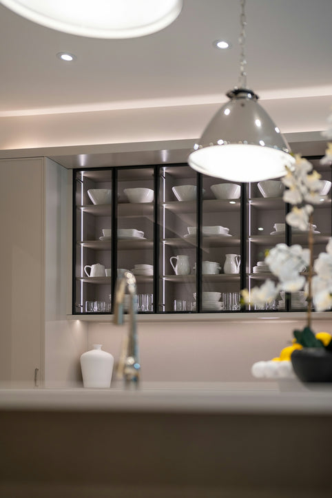 Modern kitchen with illuminated glass cabinets displaying dishes.