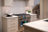 Modern kitchen with stainless steel stove, light cabinets, and cookbook.