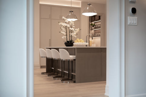 Modern kitchen island with white bar stools and orchids.