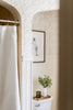 Stylish bathroom interior with framed art and plant on toilet