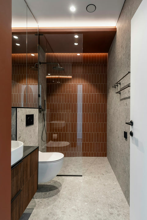 Modern bathroom with brown tiled shower and dark wood vanity.