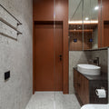 Modern bathroom with sink, toilet, mirror, and brown cabinetry.