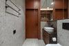 Modern bathroom with sink, toilet, mirror, and brown cabinetry.