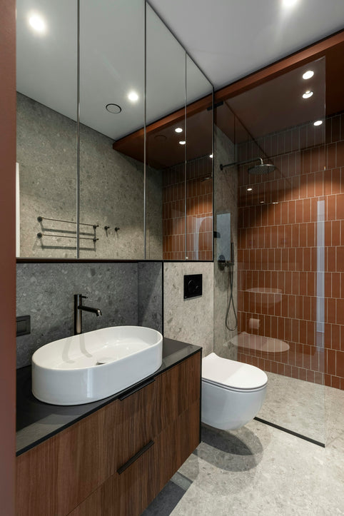 A modern bathroom with a sink, toilet, shower, and mirrors.